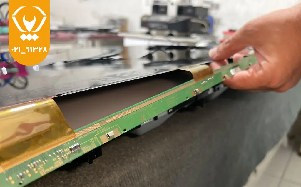 تعمیرکار در حال عیبیابی خطوط رنگی و پرش تصویر ناشی از آبخوردگی پنل