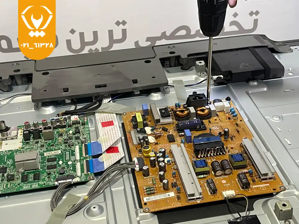 تکنسین تعمیر تلویزیون در حال بررسی برد تیکان و اتصالات داخلی برای رفع بهمریختگی رنگ